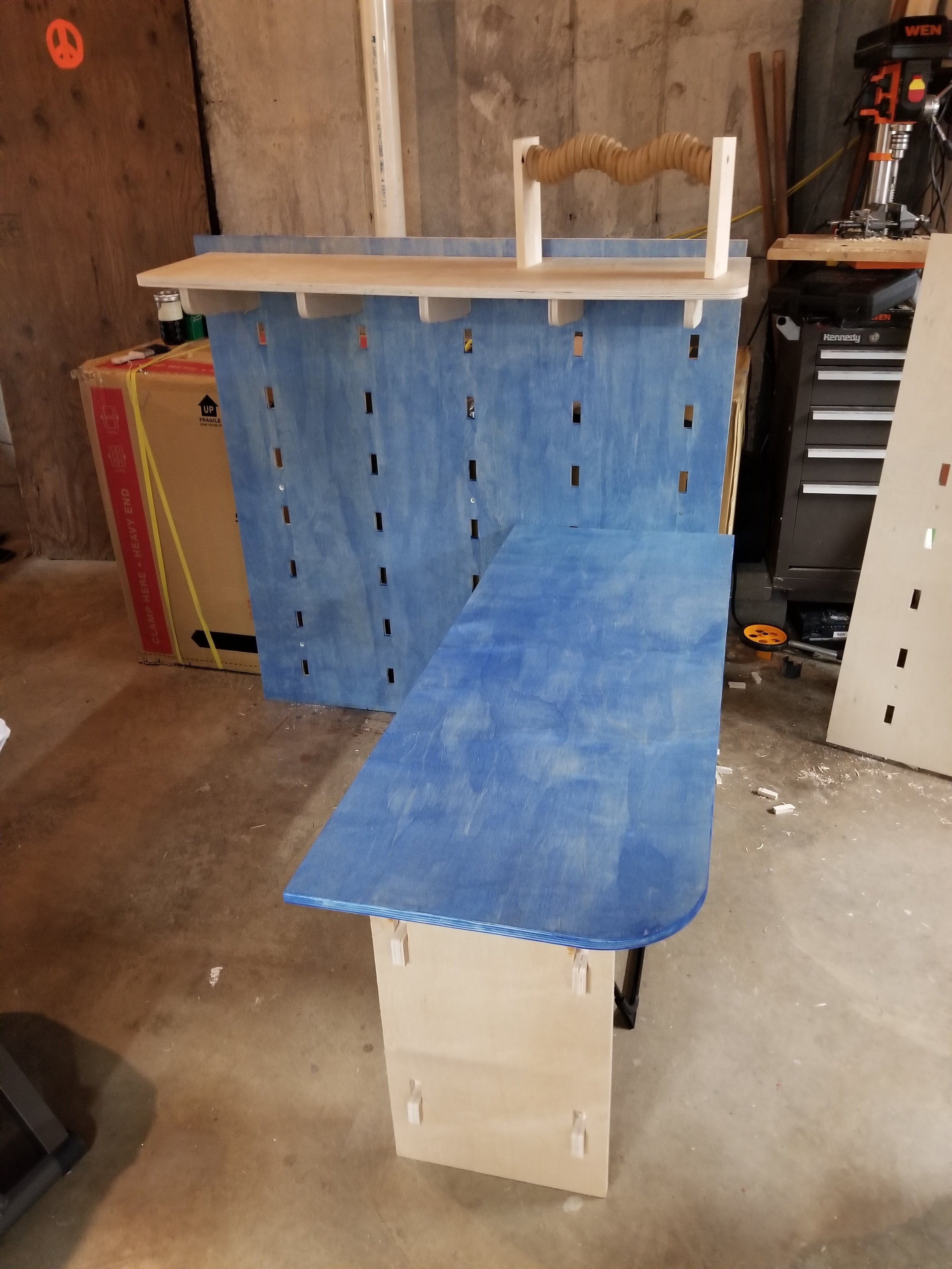 My first table. The table and the wall together costs around $50. I was able
to cut 2 shelves and the supports and 5 hooks with several parts still being
able to be cut from the same board. It is one .5 inch board and one .75 inch
board.